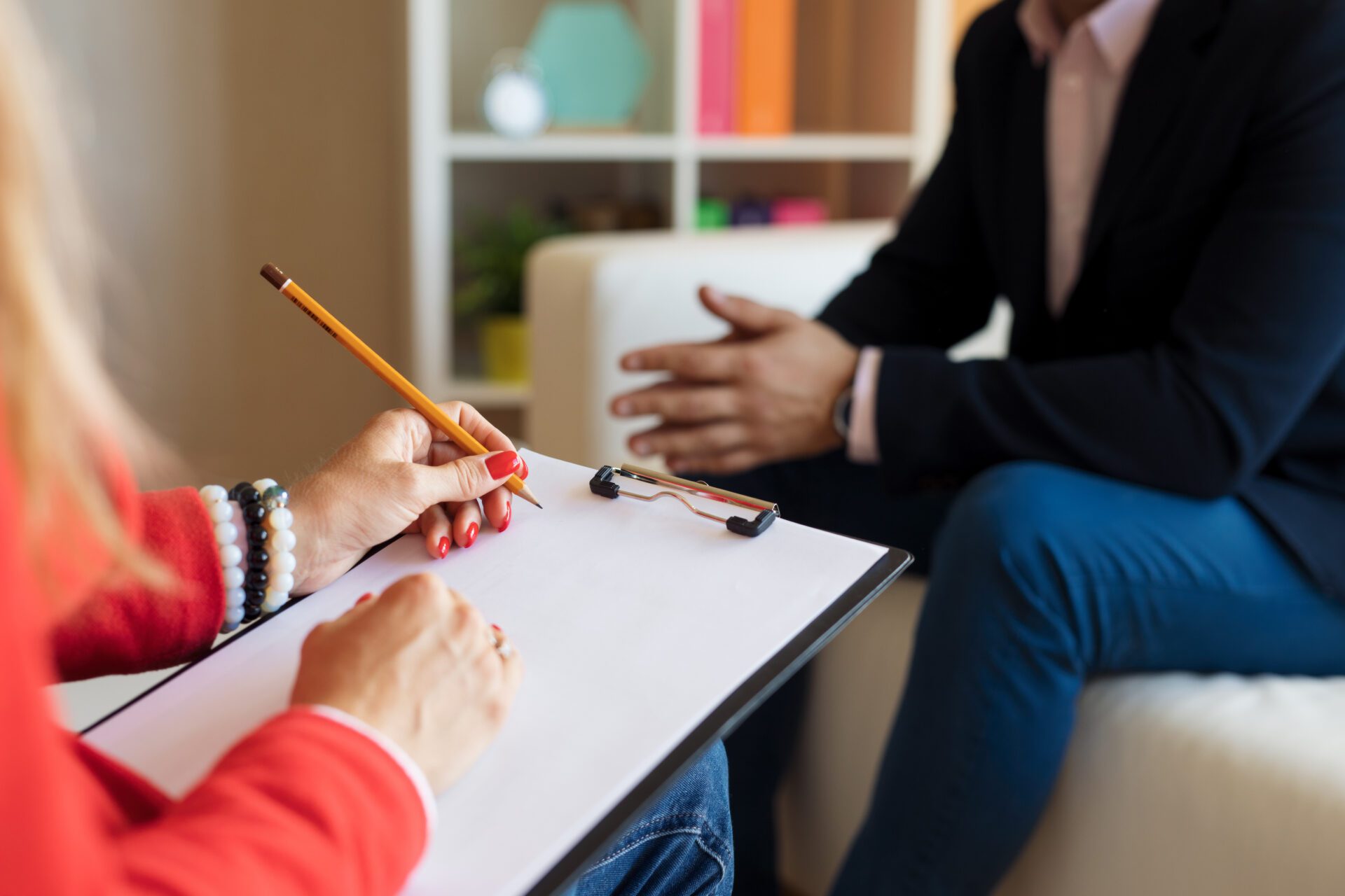 Counselor making notes while young woman crying during therapy session at office